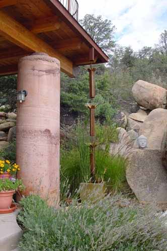 A well-integrated and artistic downspout that is part of a 20,000 gallon water –catchment system located at the entry of a Poured Earth home
